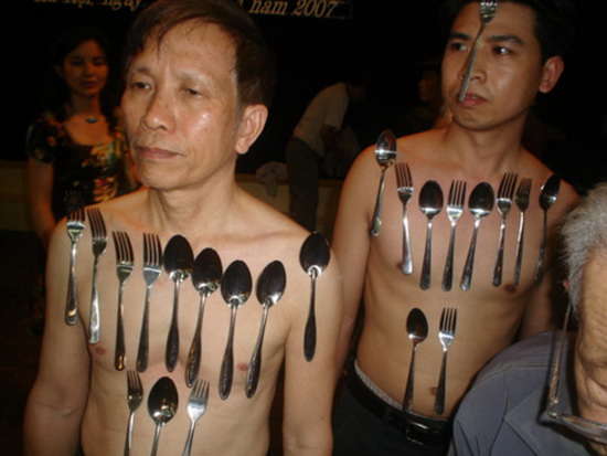 Two men with metal forks and spoons apparently stuck to their bodies